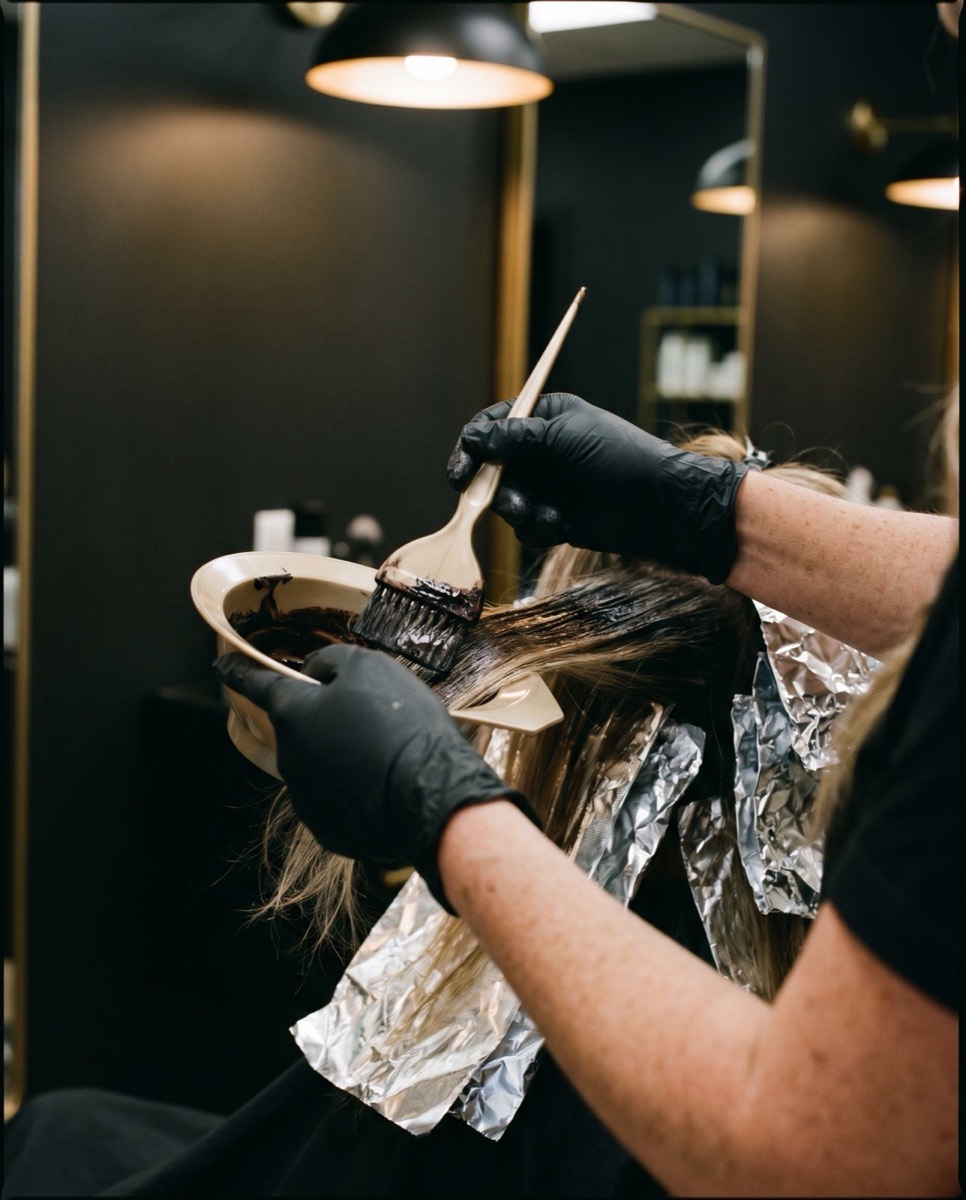 Stylist hand-applying custom color with brush and foils at Colaizzi's Hair Styling